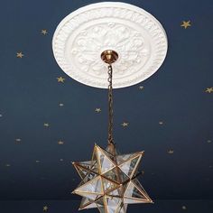 a white and gold star hanging from a ceiling with stars in the sky behind it