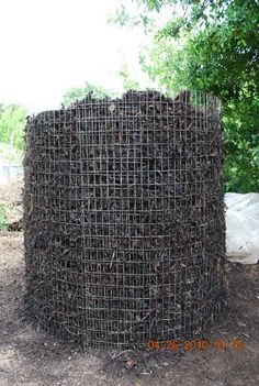 there is a large round structure made out of sticks and branches in the dirt near some trees