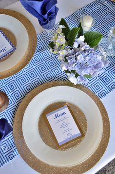 the table is set with blue and white napkins, silverware, and flowers