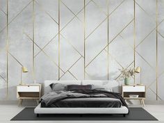 a modern bedroom with white walls and gold geometric design on the wall, along with a bed