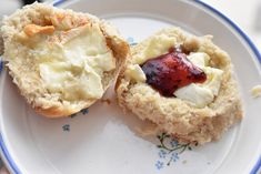 two biscuits on a plate with jam and cream in the middle one is cut in half