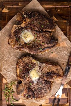 two steaks with butter and herbs on a cutting board