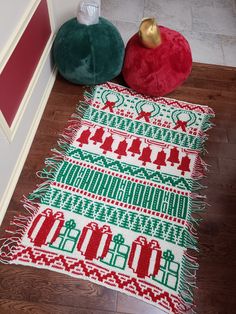 a green and red christmas tree rug sitting on top of a wooden floor next to a pillow