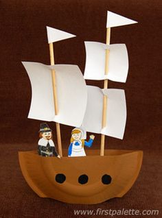 a wooden boat with white sails and two figurines on it's side