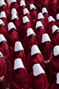 a large group of people in red and white robes, all facing the same direction