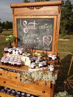 a wooden table topped with lots of jars filled with honey on top of a grass covered field