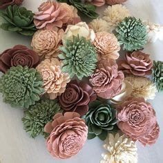 a bunch of fake flowers sitting on top of a white table cloth covered in pink and green paper