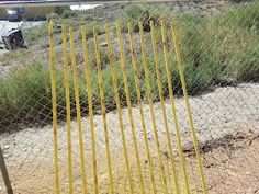 a yellow fence is in front of a field with grass and dirt on the ground