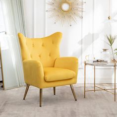 a yellow chair sitting in a living room next to a table with a plant on it