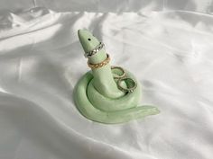 a green snake with a ring on it's head sitting on a white sheet