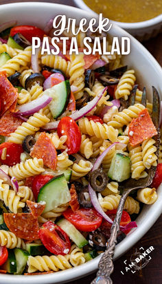 a pasta salad with tomatoes, cucumbers, olives and other vegetables in a white bowl