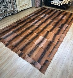 a brown and black rug sitting on top of a wooden floor next to a couch