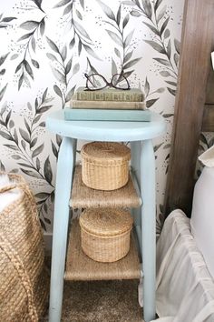 a blue table with baskets under it and a wallpapered background in the background