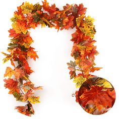 an orange and yellow leafed wreath with a round object next to it on a white background