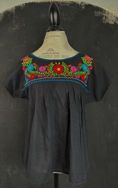 This is a nice vintage Mexican blouse. The blouse is hand embroidered on the front and the back, looks very bright and lovely. The black cotton fabric is nice to touch, quite light and gauzy. MAKE: Handmade in Mexico, no labels. CONDITION: Very good. MATERIAL: 100% cotton. MEASUREMENTS NOTE: This one does not have a size label or a vintage sizing label, please refer to the exact measurements and a sizing table I used! Bust: 100cm/39" Waist: 130cm/51" Length: 65cm/25" All my items are preloved vi Black Peasant Top For Festival, Black Peasant Blouse With Floral Embroidery, Black Embroidered Peasant Top, Traditional Black Tops With Floral Print, Black Folk Style Peasant Top, Folk Style Black Blouse For Summer, Bohemian Black Tops With Embroidered Neckline, Black Folk Style Summer Blouse, Black Cotton Folk Embroidered Top