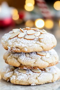 three cookies stacked on top of each other with powdered sugar and almonds in the middle