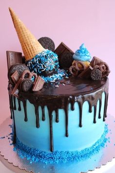 an ice cream cake decorated with chocolate, cookies and blue sprinkles on a pink background