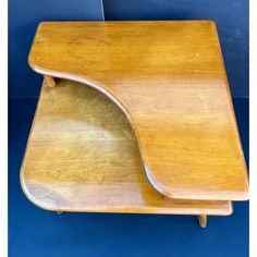 a wooden desk with a curved edge on it's top and bottom section, against a blue wall