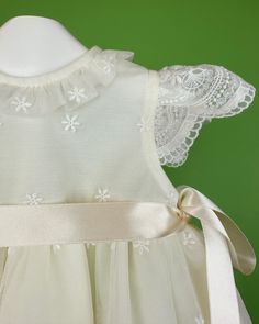 An adorable and delicate off-white dress for baby girls to wear on a special day. It is made with an embroidered french tulle. It has buttons on the back for closure and comes with a matching bonnet. Made in Spain Inside: 65% polyester 35% cotton Dry Clean Final sale, no exchanges nor returns are accepted Cream Ruffled Dress For Baptism, Cream Dress With Ruffles For First Communion, Embroidered Tulle Dress For Ceremonies, Cream Ruffled Baptism Dress For Dress-up, White Baptism Dress With Lace Bodice For Dress-up, Baptism Dress With Lace Bodice And Organza Material, Embroidered Tulle Dress In Cream, Fitted Cream Dress With Broderie Anglaise, Elegant Cream Sleeveless Baptism Dress