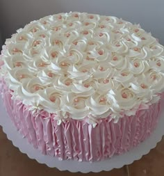 a pink and white frosted cake on a platter with icing ruffles