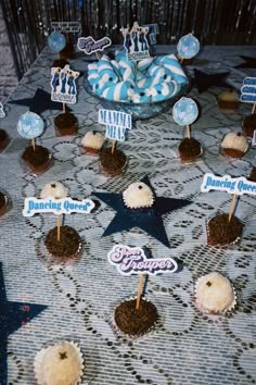 cupcakes are arranged on a table with blue and white frosted toppers