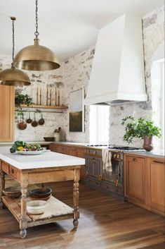 a kitchen with wooden cabinets and white counter tops, an island in the middle is surrounded by hanging pots and pans