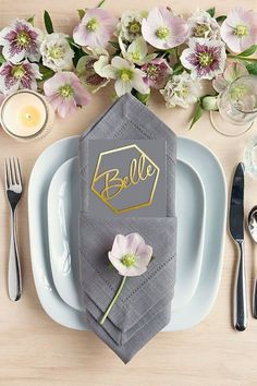 a place setting with napkins, silverware and flowers