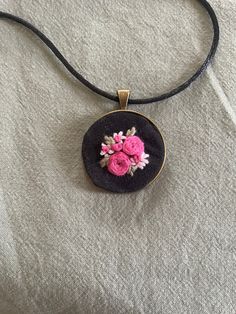 a black necklace with pink flowers on it