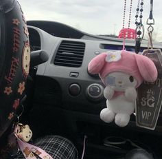 a hello kitty stuffed animal hanging from the dashboard of a car with other items attached to it