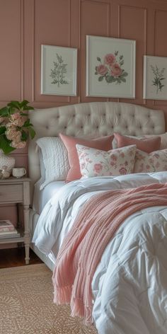 a bed with pink and white comforters in a bedroom next to two pictures on the wall