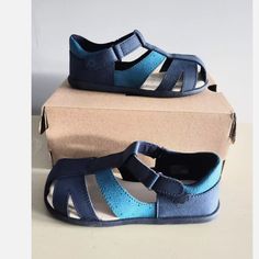 These Ugg Kylo Sandals Are Perfect For Your Little One's Summer Adventures. With A Marine Brown Color And Synthetic Upper Material, They Are Both Stylish And Durable. The Sandals Are Designed For Unisex Babies And Toddlers, And Come In A Uk Shoe Size Of 10 And Us Shoe Size Of 11t. The Kylo Sandals Feature A Comfortable Fit And A Secure Strap, Ensuring That Your Child Can Play And Explore Without Any Issues. Whether They Are Headed To The Beach Or Just Out For A Walk, These Sandals Are A Must-Hav Blue Closed Toe Sandals For Playtime, Blue Sandals With Soft Sole For Playtime, Blue Sandals With Soft Sole For Spring, Spring Blue Sandals With Soft Sole, Blue Non-slip Sandals For Playtime, Adjustable Blue Sandals For Playtime, Navy Non-slip Sandals For Summer, Blue Closed Toe Sandals With Soft Sole, Blue Adjustable Non-slip Sandals