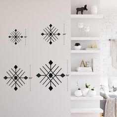 a living room with white walls and black decorations on the wall, along with shelving units