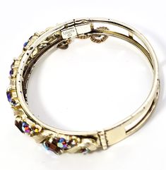 Lisner topaz and aurora borealis mid century signed vintage bangle bracelet. Good used condition with little to no signs of normal wear. No missing stone. Safety chain is still intact. Stamped on the inside of the band Lisner. Bracelet measures 6 and 3/4ths of an inch around and 3/8ths of an inch wide. Vintage Jeweled Cuff Bracelet For Formal Occasions, Vintage Jeweled Bangle Bracelet, Vintage Jeweled Bangle Cuff Bracelet, Vintage Adjustable Jewelry With Rhinestones, Vintage Gold Bangle With Jewels, Vintage Jeweled Bangle, Vintage Jeweled Bangle For Wedding, Vintage Jeweled Wedding Bangle, Collectible Costume Jewelry Bangle