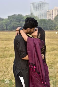 a man and woman are kissing in a field