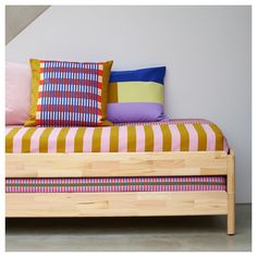 a bed with colorful pillows on top of it and a stair case in the background