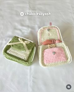 two crocheted suitcases sitting next to each other on a white sheet with a ribbon