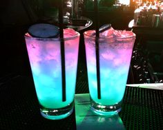 two tall glasses filled with liquid sitting on top of a table next to each other