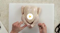 a person holding a piece of chicken on top of a cutting board next to scissors