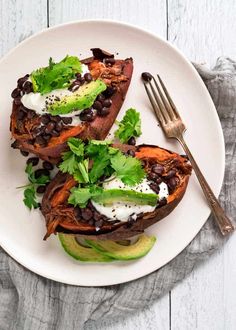 two stuffed sweet potatoes topped with black beans, avocado and cilantro