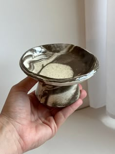 a hand is holding a small bowl with something in it