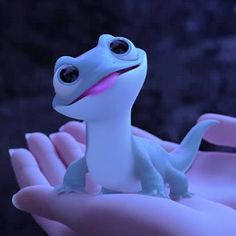 a close up of a person's hand holding a toy gecko