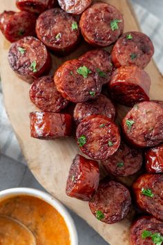 cooked sausages on a cutting board with dipping sauce