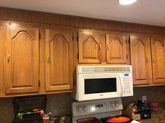 a white microwave oven sitting on top of a counter next to wooden cabinets in a kitchen