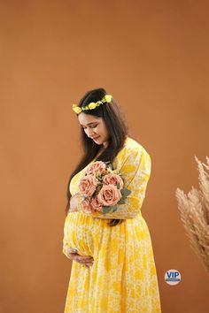 a pregnant woman in a yellow dress holding flowers