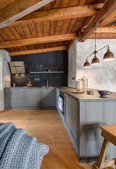 an open kitchen with wooden floors and gray cabinets is pictured in this image from the living room