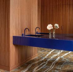 a blue counter top in a kitchen with wooden cabinets and marble flooring on the walls