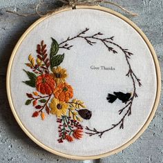 a cross - stitch hoop with flowers and birds on it that says give thanks in the center