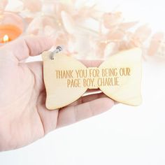 a person holding a wooden bow tie with the words thank you for being our page boy charlie