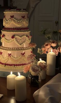 a wedding cake sitting on top of a table next to candles