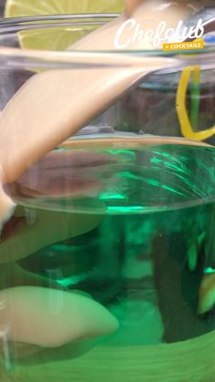 a glass jar filled with liquid next to lemon wedges